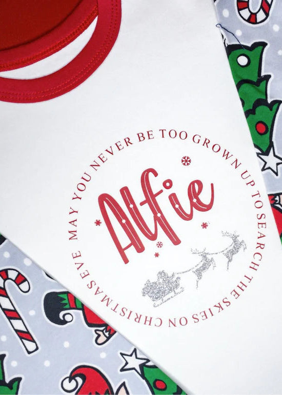 A white Christmas-themed adults' sleeping shirt with red collar and cuffed bottoms, featuring text and decorative elements related to the holiday season.