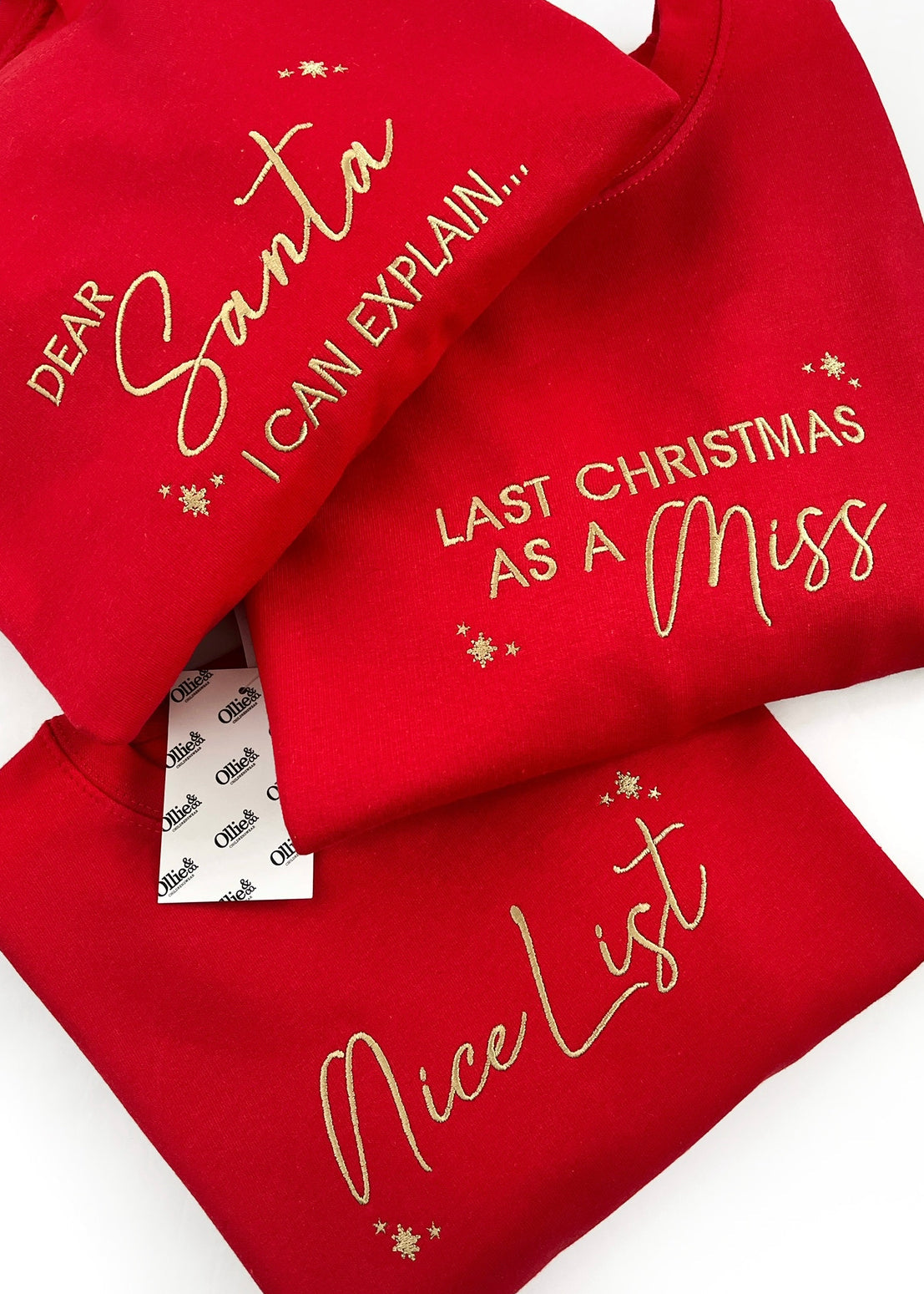 Three red Christmas-themed sweaters with embroidered designs, including text and decorative elements.