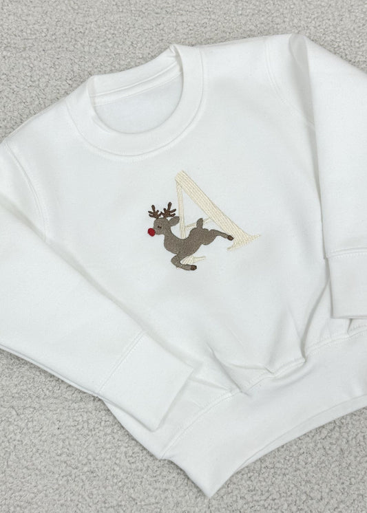White baby sweater with reindeer and an embroidered initial on the front.