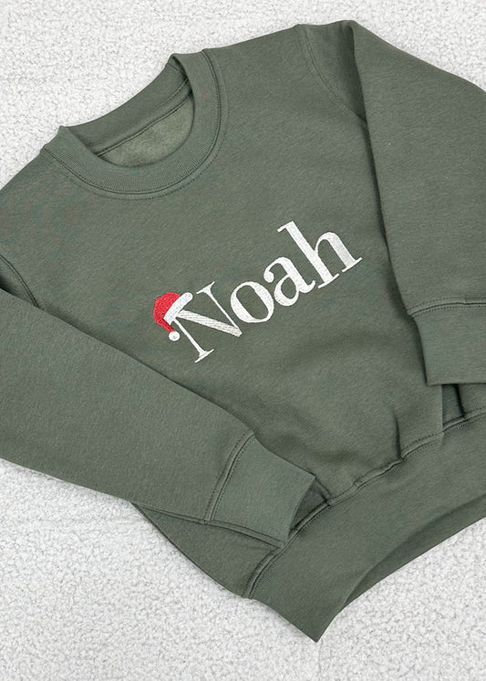 A green Christmas themed sweater with 'Noah' embroidered in white on the front.