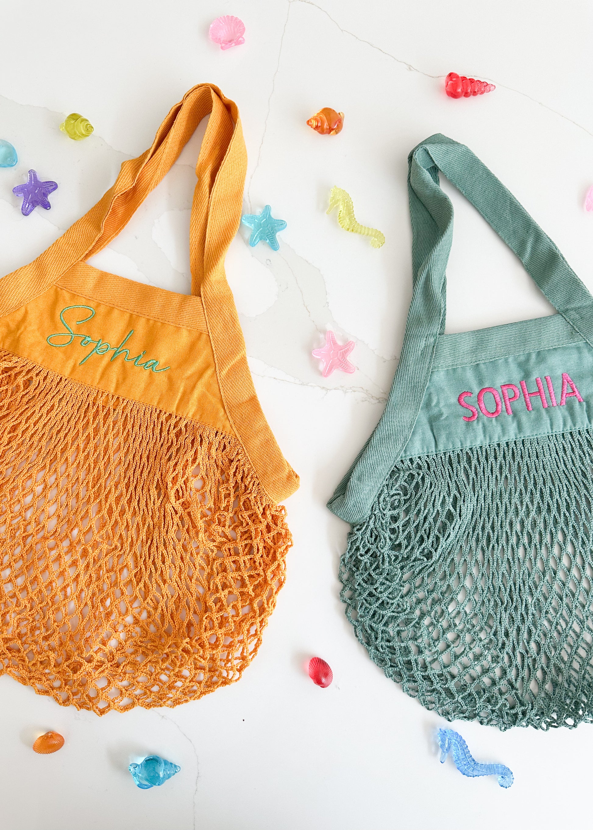 Two mesh bags, one orange and one green, with 'Sophia' embroidered on them, on a white background with colorful starfish decorations.