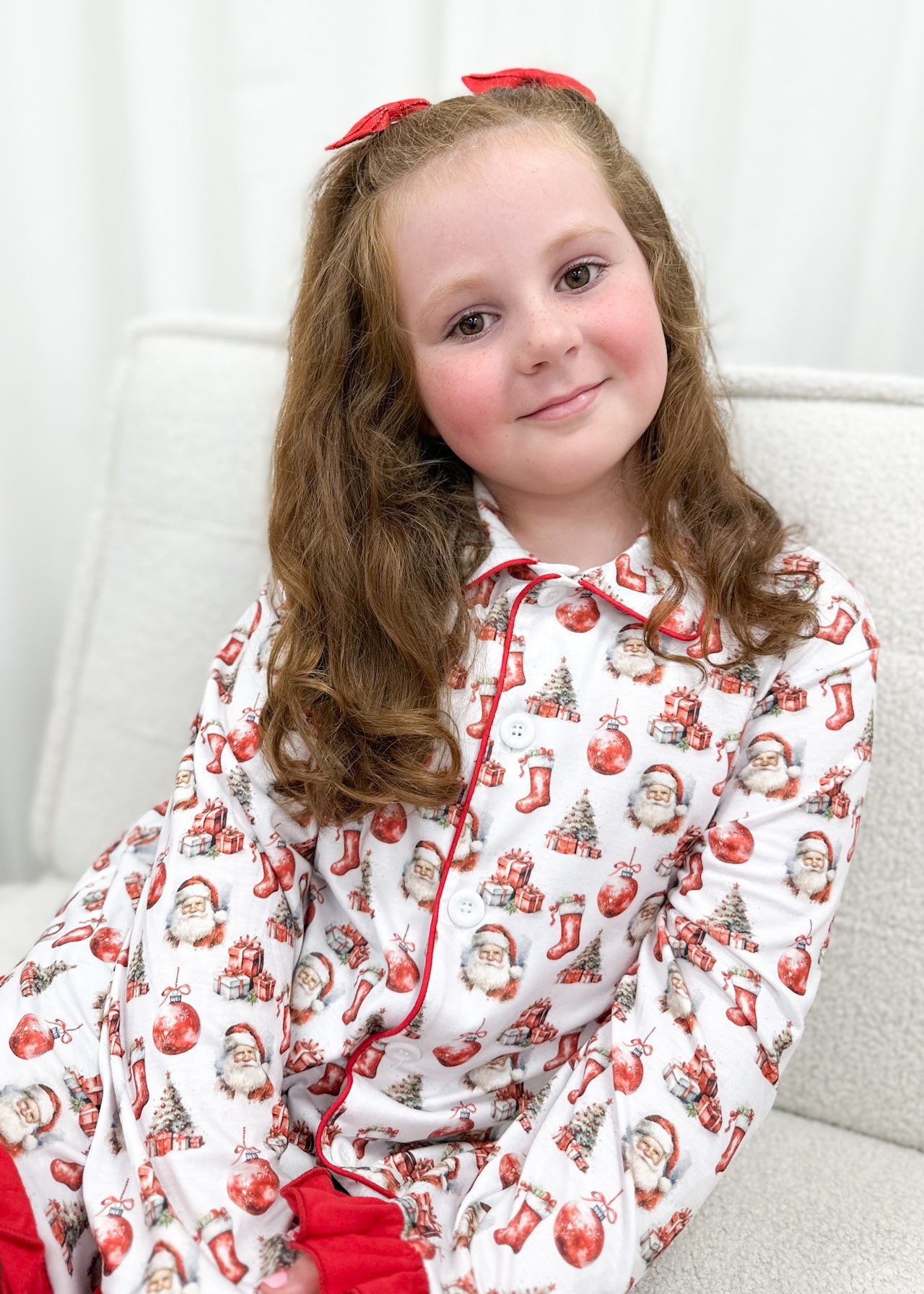 Young girl wearing a festive pajama set with Santa Claus and Christmas elements.