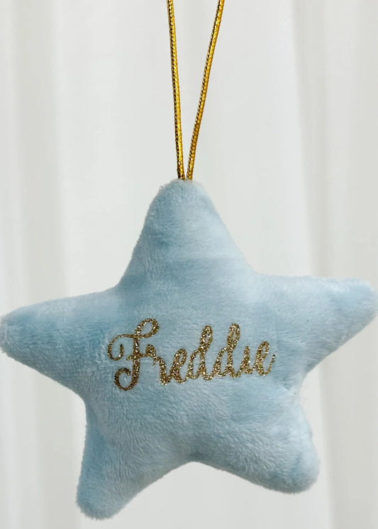 A blue star-shaped decoration with the name 'Frederic' embroidered in gold, with a golden chain for hanging.