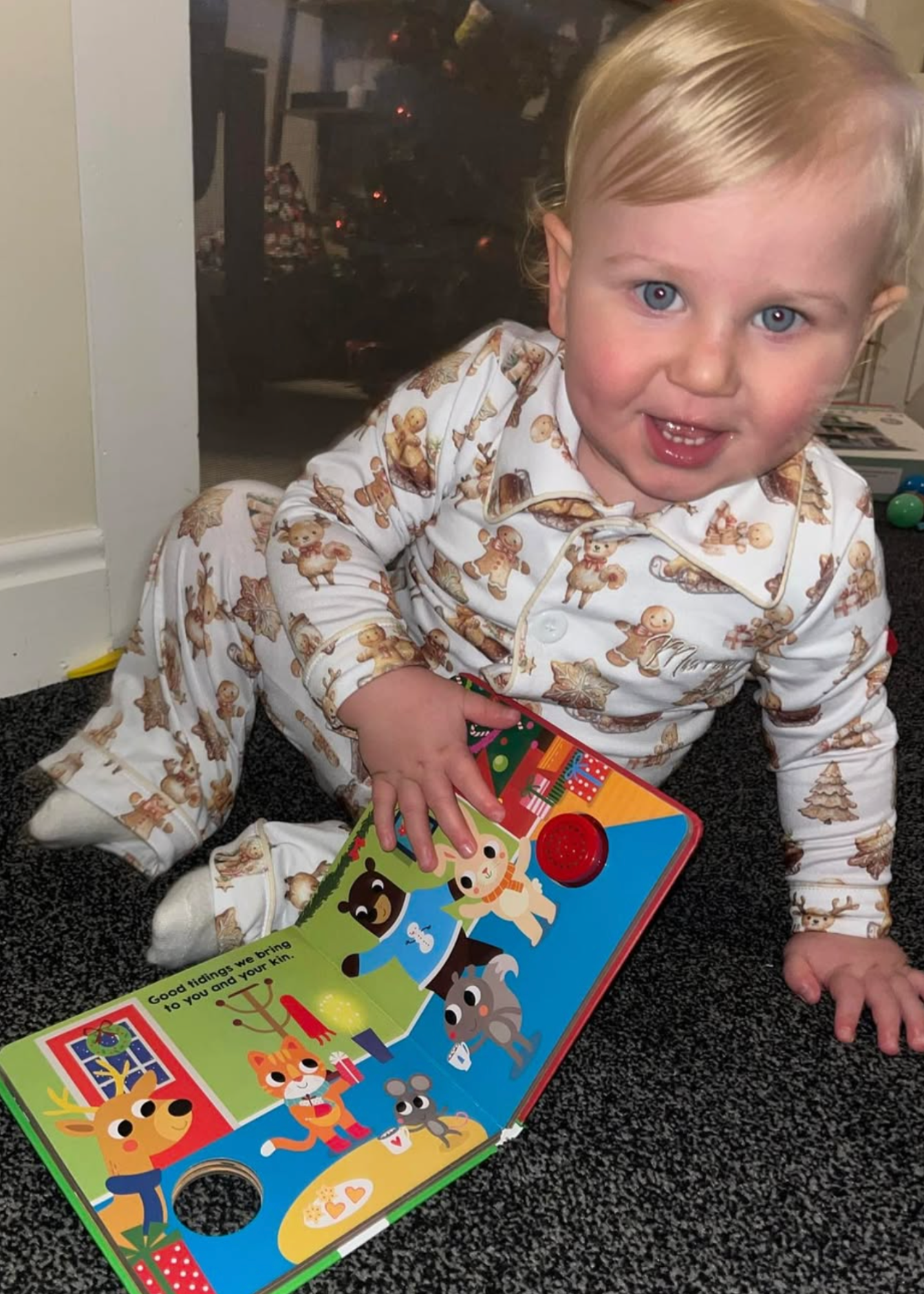 Child in pajamas with a colorful book on a carpeted floor