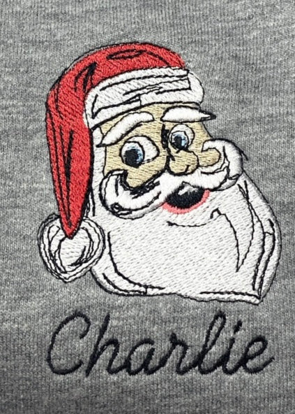 A grey romper with an embroidered image of Santa Claus wearing a red hat and a white beard, and the name 'Charlie' below it.
