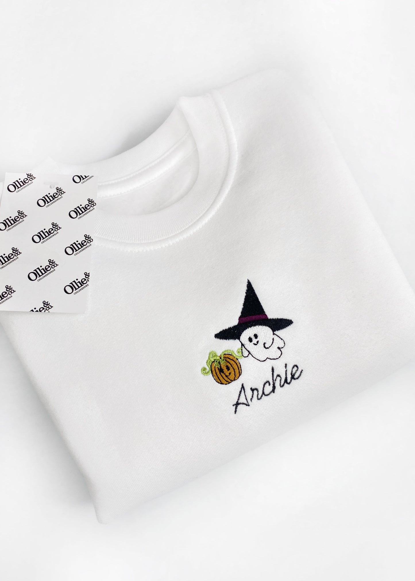 White jumper with a small graphic of a character, presumably 'Annie', with a pumpkin and leaves on the chest.