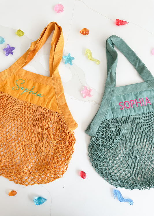 Two mesh bags, one orange and one green, with 'Sophia' embroidered on them, on a white background with colorful starfish decorations.