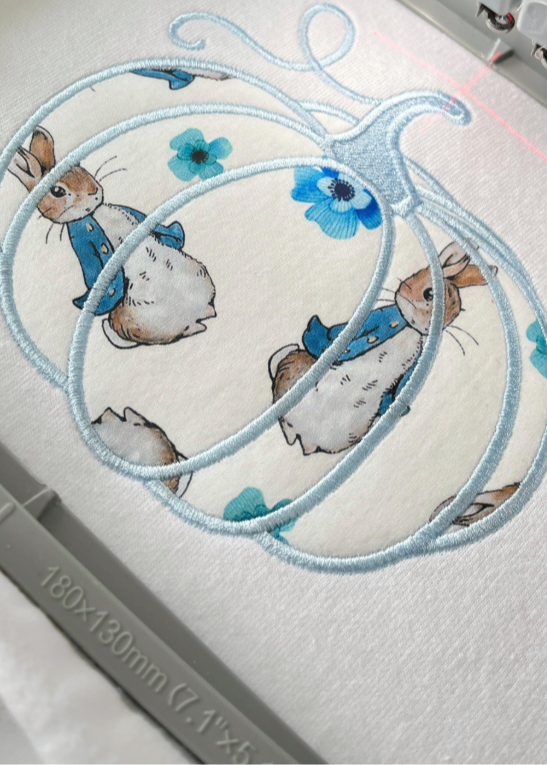 Embroidery design with cartoon rabbits and flowers on a white fabric background